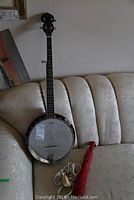 Overview of banjo leaning on sofa with red umbrella and white cord coiled at base