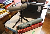Photo showing both scopes on table: the Bausch and Lomb Balscope Zoom 60 mounted on tripod and the Bushnell Spacemaster II in its carrying case alongside a boxed item.