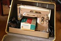 Vintage Singer sewing machine model 403 inside a beige carrying case with power cord and a box of attachments.