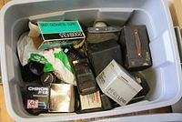 Top view showing an assortment of camera lenses in boxes, camera cases, and camera flash units.