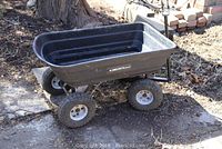 Full side view of the Gorilla Cart garden cart showing the poly bed and four off-road tires with some dirt.