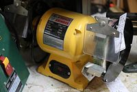 Front angle view of yellow 6 inch bench grinder showing the model and general condition