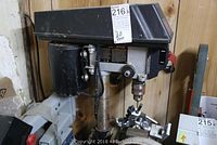 Full view of Skil drill press showing motor housing, vertical support column with rust, and base with clamp assembly.