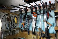 Overview of pegboard with clamps, saws, levels, squares, rotary tool, sanding belts