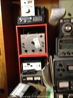 View of shelf with multiple electronic devices including a resistance capacitance comparator bridge and scanner unit in black with numeric keypad