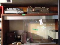 Photo of shelf with multiple vintage projection and audio units including the Zeiss Ikon Movilux S8 projector and related equipment.