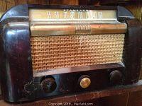 Close-up photo of small RCA Victor radio showing dial with AM band and three control knobs; surface scratches visible.