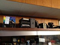 Shelf display of multiple vintage folding cameras and a product box