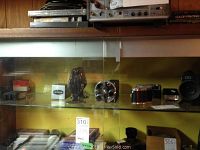 Photo showing vintage cameras and film projector in glass display cabinet, Canon rangefinder, Bell and Howell Auto Master projector, and other items visible.