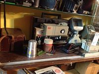 Elmo ST-180E projector, Canon camera in case, and Moviscop flash unit on shelf with other accessories