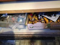 Wide view of two cardboard boxes containing various camera accessories, adapters, and filter boxes mostly in yellow and blue colors.