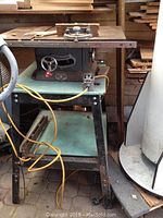 Front view of vintage Beaver Power Tools table saw on metal stand with visible rust and wires.