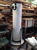 Full view of the white telescope tube and Dobsonian base among workshop lumber