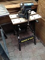 Overall view of the workbench with metal vise mounted on top, showcasing the perforated work surface and labeled metal legs.