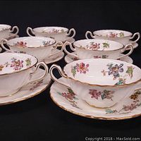 Group of six bowl-and-underplate sets showing floral design and gilt edging