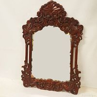 Full frontal view showing the heavily carved wood frame surrounding the rectangular mirror.