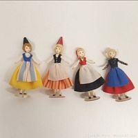 Four micro miniature handmade dolls lined up showing variety in dresses and hats.