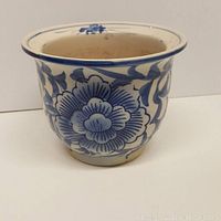 Side view of the pottery planter showing blue floral patterns on white ceramic surface.