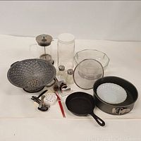 Photo showing the entire kitchen collection including colander, cast iron pan, glass bowl, French press, salt and pepper shakers, and other items