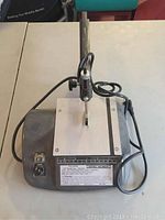 Top view of Central Machinery 12 inch scroll saw showing the blade, work surface, power cord, and switch.