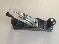 Side angle view of Stanley hand planer model 12-204 showing metal body, wooden handle, and blade adjustment lever.