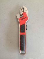 Top view of the Black and Decker electric adjustable wrench showing the red body, adjustable jaw size markings, rubber grip, and control switch.