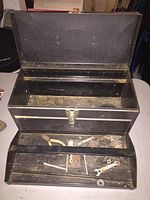Top view of black Simmonds metal tool box open showing upper compartment with minor surface rust and dirt.