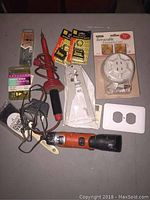 Mixed lot including cordless drill, retractable extension cord, tape measures, outlet covers, wire stripper, soldering iron, and sewing pins.