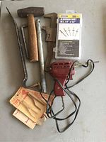Photo showing the lot items arranged on flat surface: rivet gun, hammer, wrenches, aluminum rivet set in packaging