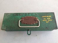 Closed green metal Greenlee No. 830 hole saw set case showing surface rust on latch and handle, seller's name marked on top