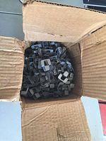 Cardboard box filled with numerous metal plywood brackets.