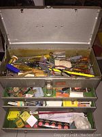 Close-up of top compartment of toolbox with various hand tools and components visible.