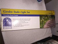 Box front showing product name Garden Stake Light Set and Victorian Street Lamps along with image of garden stake lights illuminating a pathway.