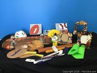 Photo showing various sports-related items including mini hockey sticks, baseball glove, soccer ball, Mr Happy water bottle, wooden picture frames, and green swimming fins.