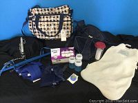 Photo showing most items in the lot including the diaper bag, Jolly Jumper, Snugli baby carrier, sleep sac, laundry bag, travel mug, Philips Avent bottles, and additional small parts for bottles or nipples.