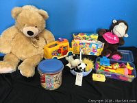 Two stuffed animals (large beige teddy bear and brown monkey with pink bib), a VTech Count and Learn School Bus toy, Play Doh sets including a 40-piece cookie cutter set, various Play Doh cutters, and small stuffed animals in a bowl.