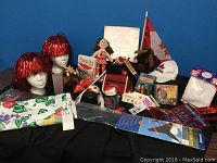 Photo showing a collection of Canada Day celebration items including flag, wigs, moose figures, tote bag, game, book, pencil, and accessories.