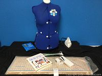 Full lot view showing dress form, cutting board, sewing book, manual stitcher, iron