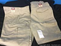 Two pairs of khaki men's cargo pants folded, showing front and back sides with flap pockets and belt loops.