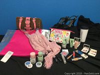 Full lot display showing Clinique makeup items, bags, shoes, scarf, and travel mug arranged on black cloth.