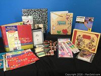 Photo showing three scrapbooking albums, a school organizer, several greeting cards, paint brushes, and crafting materials
