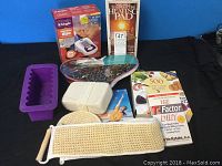 Full view of all health and fitness items including blood pressure monitor box, heating pad box, books, loofas, back scrubber, and silicone mold on a black surface with blue background.