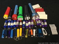 Full view of assorted flashlights and battery packs showing variety of sizes and colors arranged on a black surface.