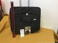 Front view of black travel bag with carry handles and a ruler showing size