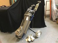 Golf Trends golf bag on a pull cart with white golf shoes on the floor in front