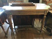Front view of wooden hall table showing empire legs and decorative carvings.