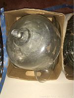 Top view of glass cake platter with dome lid inside a cardboard box.