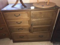 Full view of the small hardwood chest showing four drawers and a cabinet door with metal handles and keyhole.