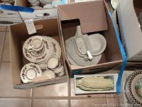 Box containing set of assorted Myott Staffordshire Indian Tree pattern dishware including plates, cups, and a gravy boat, and corn-shaped plates in separate box.