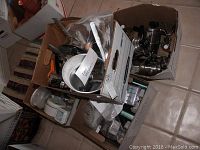 Boxes containing kitchen tools including metal utensils, graters, sieves, and other kitchen accessories.